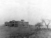 Campus View, 1916:  The Administration Building with its new auditorium wing completed in 1916.  Also shown are "The Pines", planted in Spring of 1915 as a wind break by Mr. Delford Cottrill's agriculture and botany classes, and later to grow to become a noted feature of "The Campus Beautiful".